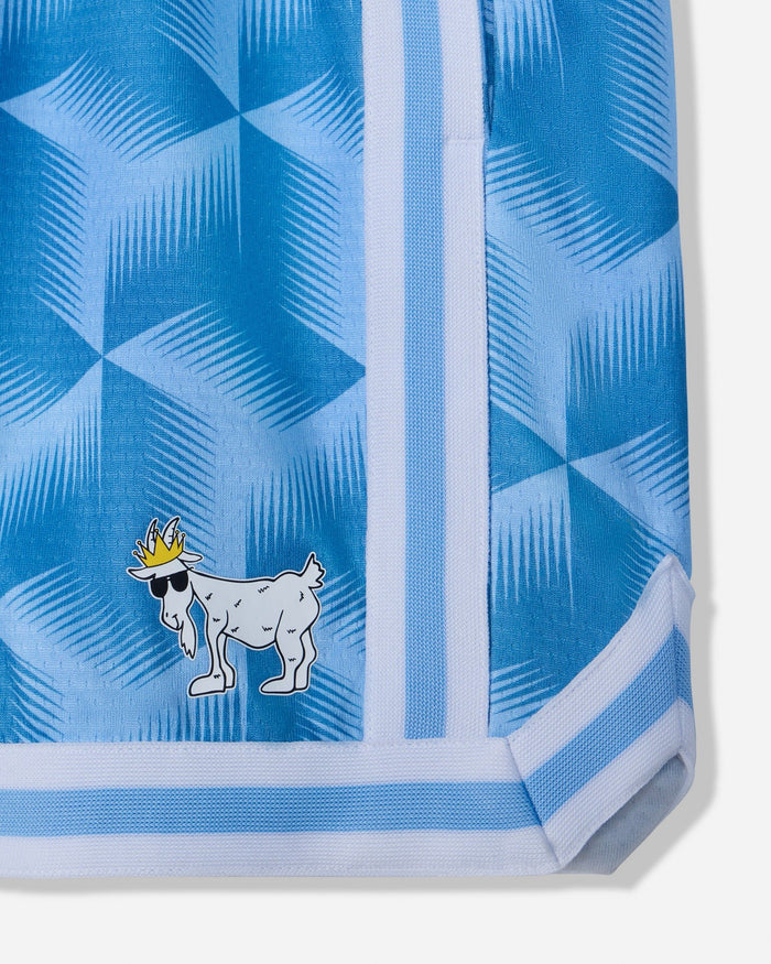 Close-up of a light blue patterned garment, likely shorts or a skirt, featuring a white and blue geometric design, a vertical white stripe, and a small cartoon goat wearing a gold crown near the lower left.#color_carolina-blue