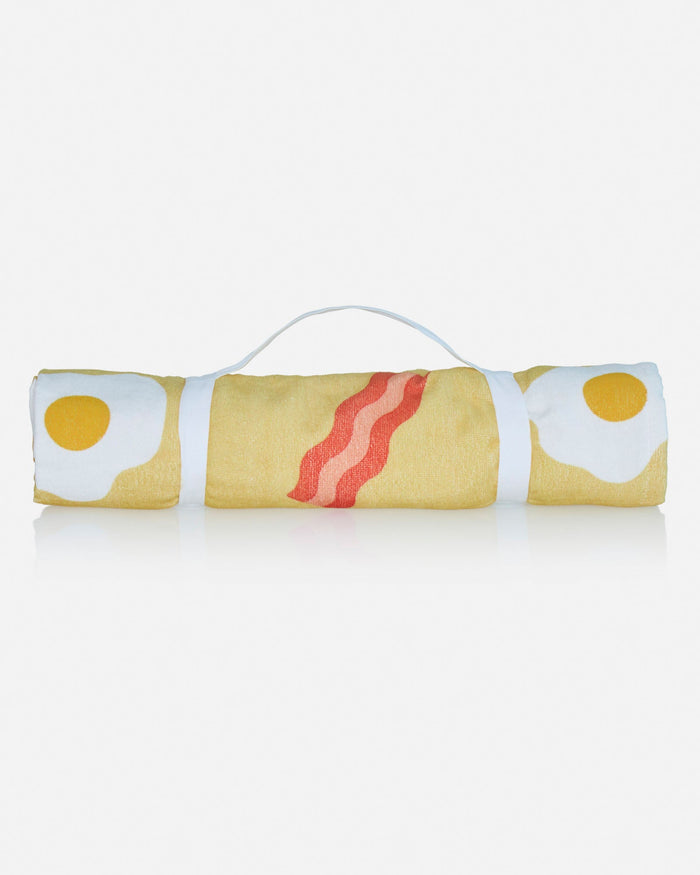 Rolled up beach towel with bacon and eggs pattern