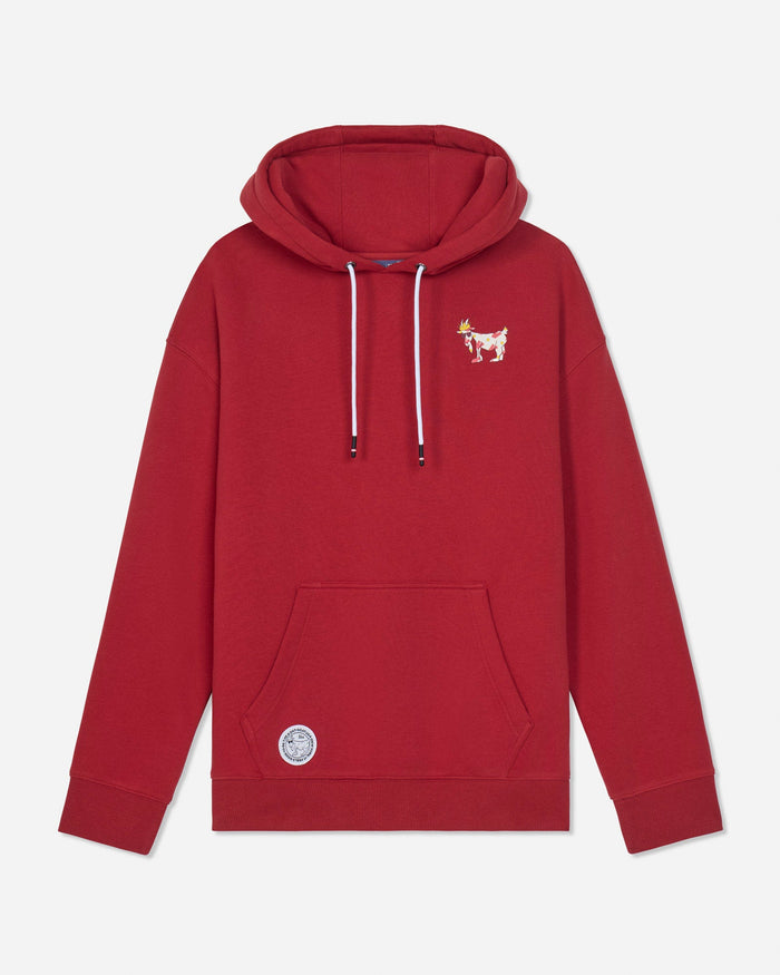A red pullover hoodie with white drawstrings, featuring a small embroidered goat logo on the left chest and a circular patch near the bottom pocket, displayed on a light gray background.