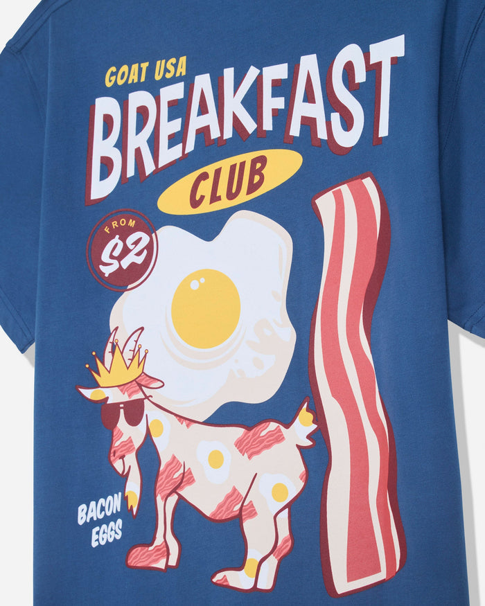 Close-up of blue t-shirt with bacon and eggs goat design with text that reads 'GOAT USA BREAKFAST CLUB'