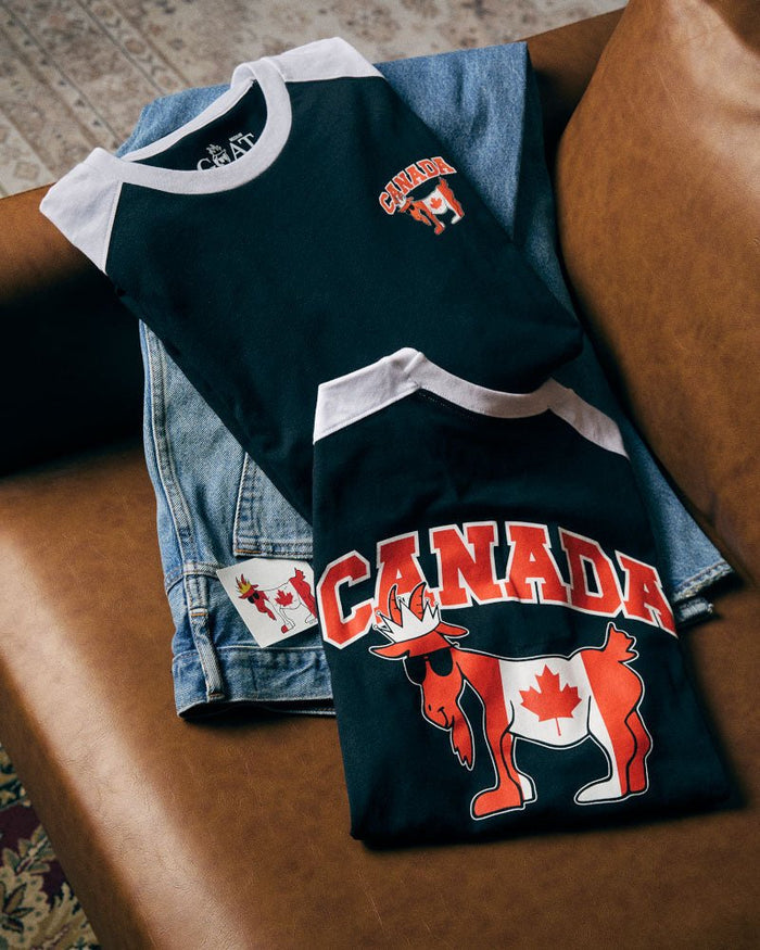 Black t-shirt with 'Canada' and goat design on a leather couch