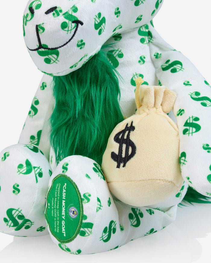 A plush goat toy in a white fabric printed with green dollar signs, featuring bright green faux fur around the neck and holding a small beige plush money bag with a black dollar sign.