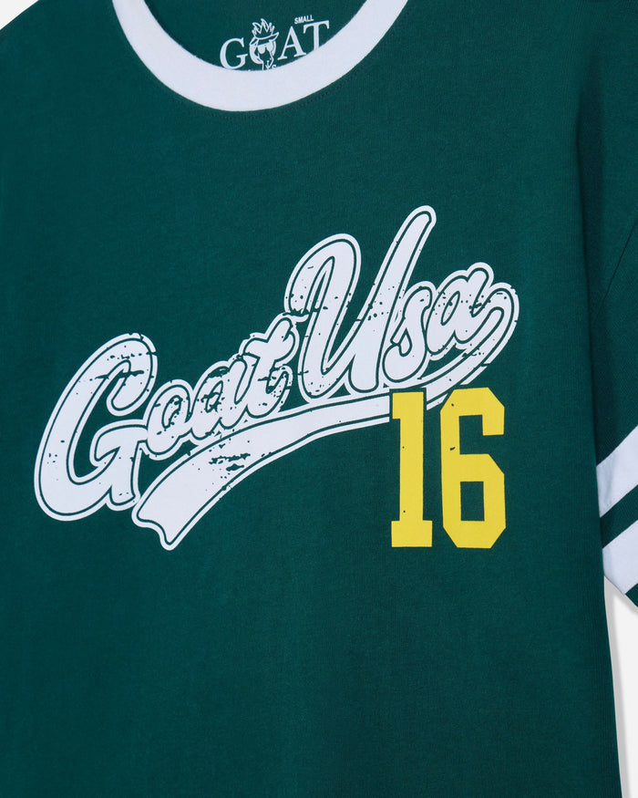Close-up of a dark green GOAT t-shirt featuring a distressed white 'Goat Usa' script logo and a yellow '16' printed on the front.