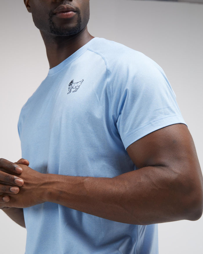Man wearing a light blue t-shirt with a small logo on a plain background#color_carolina-blue
