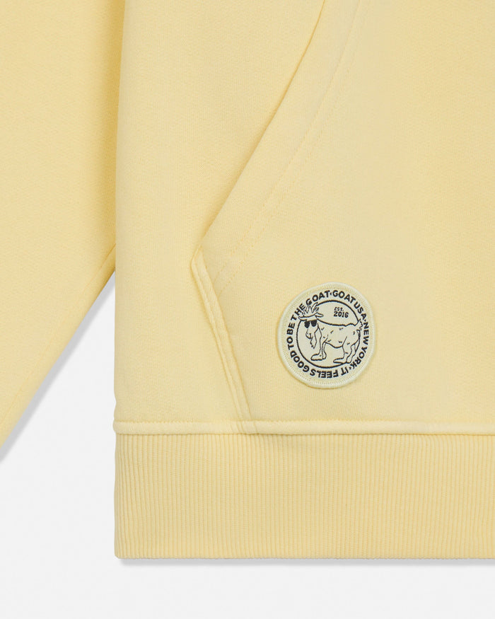Close-up of a yellow garment with a brand logo on a white background