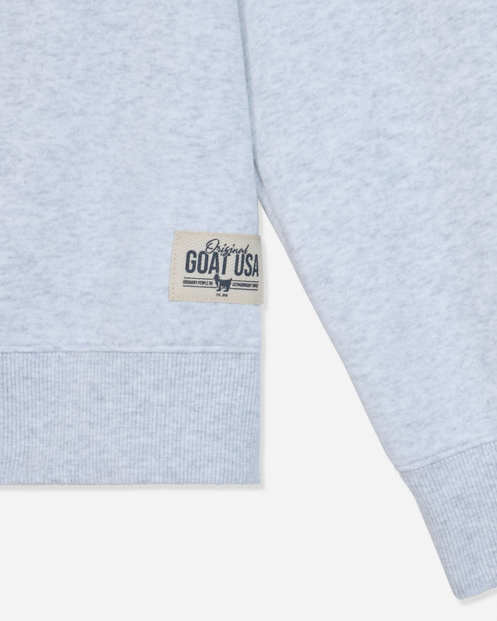 Close-up of a light heather gray sweatshirt sleeve with a ribbed cuff and a small beige woven label reading 'Original GOAT USA' on a white background.