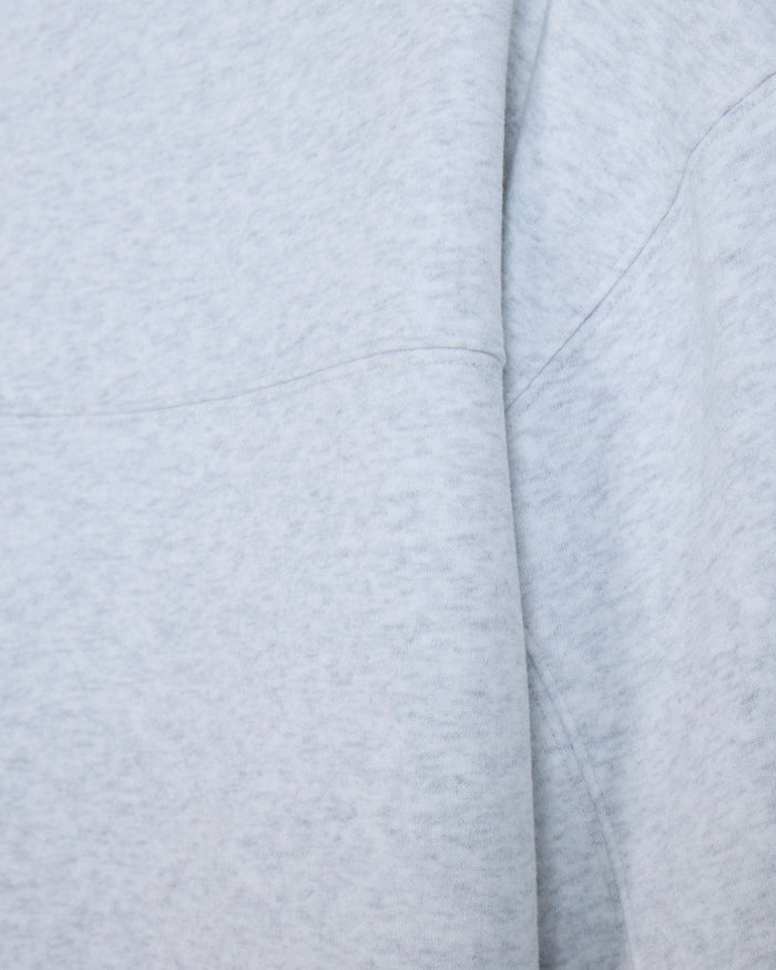 Close-up of a light heather gray fabric with soft folds and stitched seams.