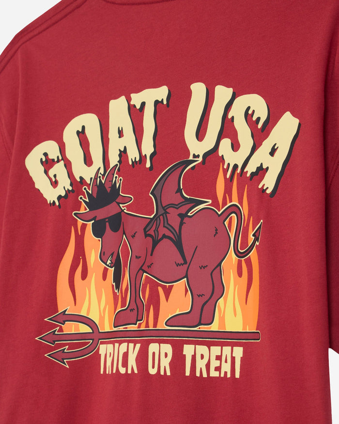 A close-up of a red graphic t-shirt featuring a cartoon dragon goat wearing sunglasses and a hat, standing in front of flames. The text 'GOAT USA' is written above in a dripping cream font, and 'TRICK OR TREAT' is written below.