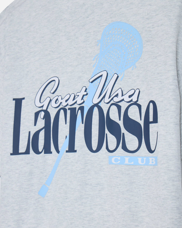 Close-up of a light heather gray garment featuring a navy and light blue graphic that reads 'Gout Usa Lacrosse CLUB' with a lacrosse stick illustration.
