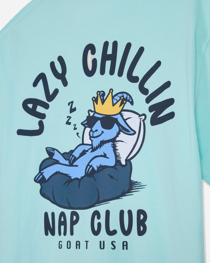 Close-up of mint t-shirt with goat laying in bed graphic and text that reads 'LAZY CHILLIN GOAT USA NAP CLUB'