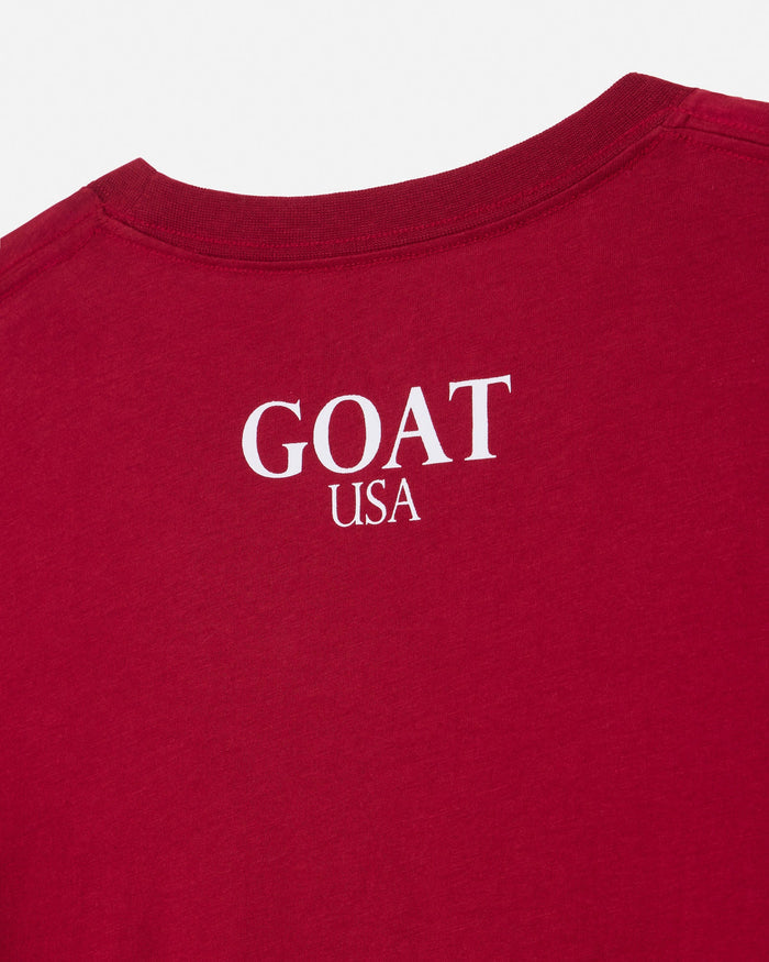 A close-up of a red t-shirt showing the back collar and upper back with 'GOAT USA' printed in white text.#color_cranberry