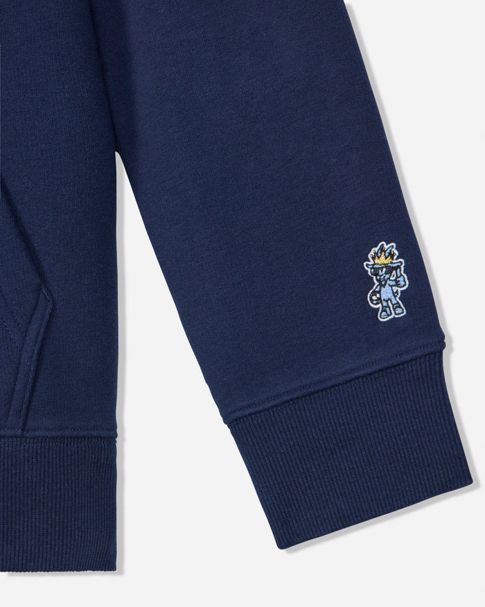 Close-up of a navy blue ribbed sweatshirt sleeve with a small embroidered cartoon character on the cuff, shown against a light gray background.