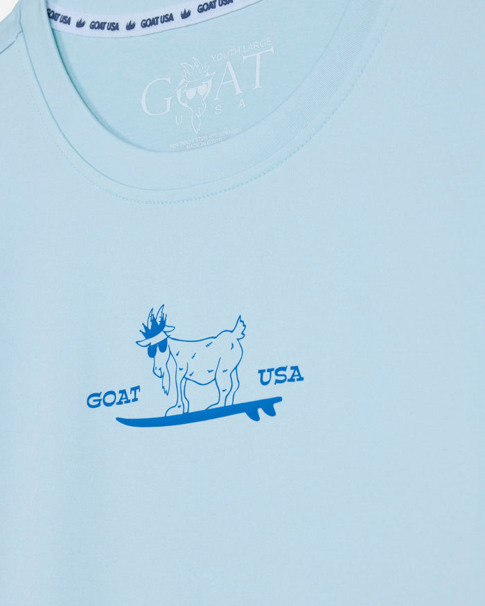 Light blue t-shirt with a graphic of a goat on a surfboard and 'GOAT USA' text.#color_delicate-blue