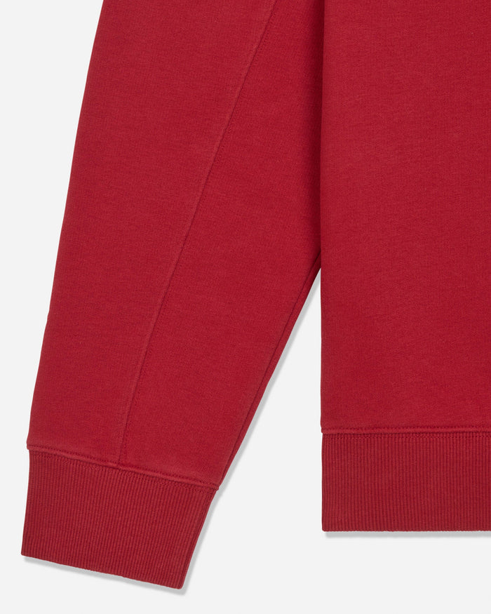Close-up of a red sweatshirt sleeve with ribbed cuff, shown against a light gray background.