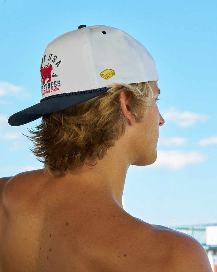 Side-view of man wearing a backwards hat with a clear blue sky in the background