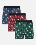 Three pairs of men's boxer briefs in holiday-themed plaid patterns, displayed in a staggered stack on a light gray background. The top pair is navy blue and black with white goat prints, the middle pair is red and black with white goat prints, and the bottom pair is green and black with white goat prints.
