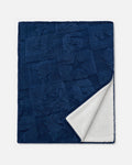 A navy blue textured throw blanket with a white sherpa lining, shown folded to display both sides against a light gray background.