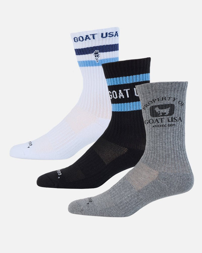 Three pairs of Goat USA crew socks in white, black, and heather gray, arranged diagonally against a light gray background.