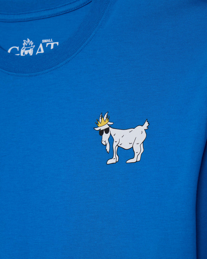 Close-up of a bright blue t-shirt featuring a white cartoon goat wearing a gold crown and black sunglasses on the chest, with a white 'SMALL GOAT' logo printed inside the collar.#color_french-blue