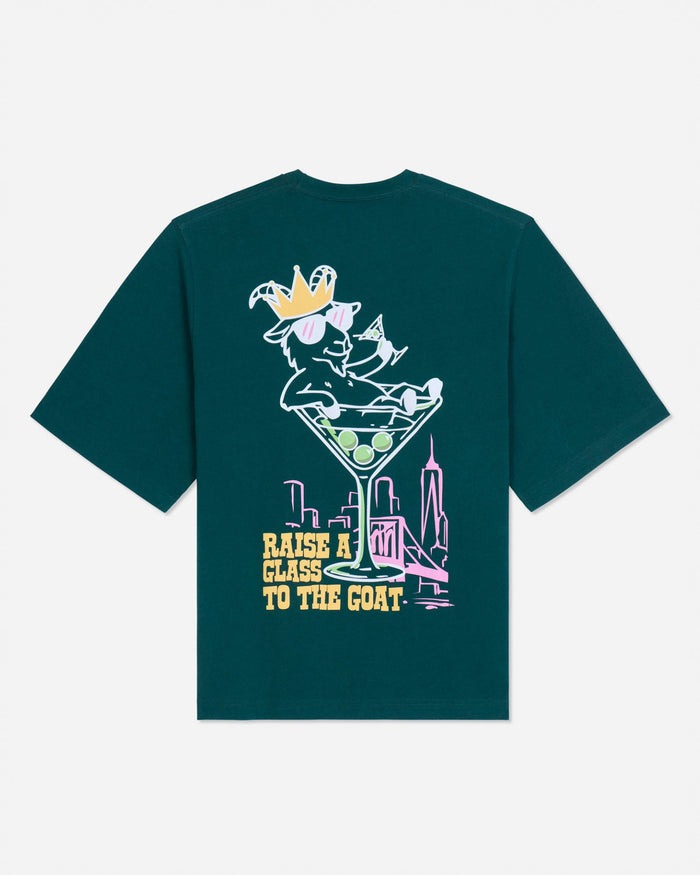 Back of sage t-shirt with martini glass goat graphic and text that reads 'Raise a glass to the GOAT'