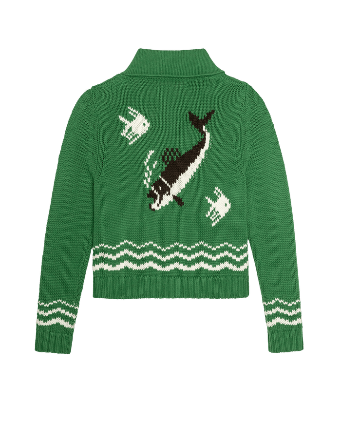 The Bass Cardigan - Grove by THE GREAT. SU26 is a green knit cardigan with a white wave pattern at the hem and three fish designs on the back, including a large black and white fish.
