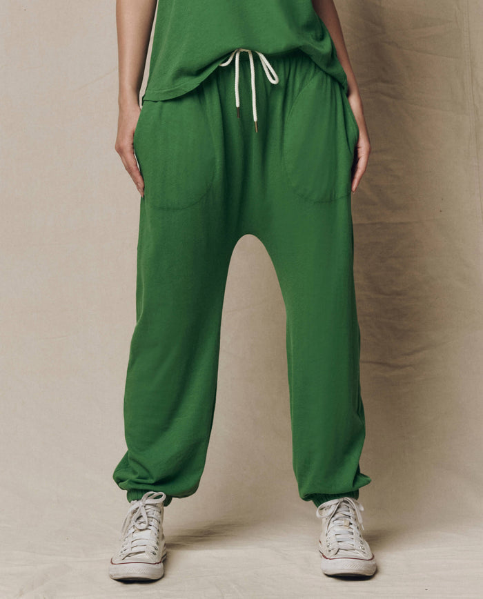 Model wears THE GREAT. SU26 SEASONAL CORE The Jersey Jogger Pant in Fennel, featuring large front pockets and paired with white sneakers, against a neutral background.