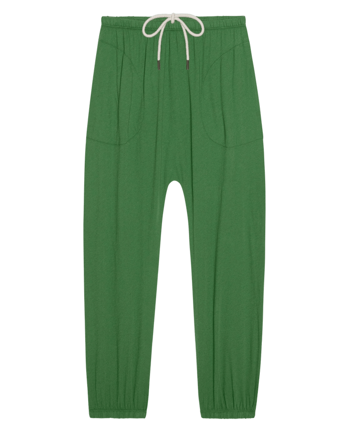 The Jersey Jogger Pant in Fennel by THE GREAT. SU26 SEASONAL CORE features an elastic waistband, white drawstring, side pockets, and elastic cuffs, shown on a white background.