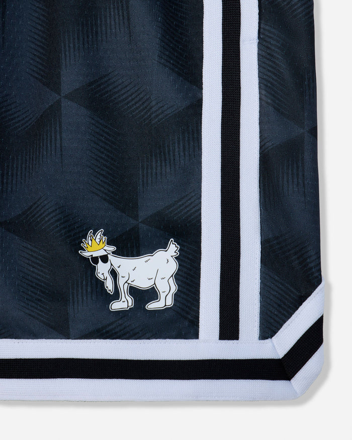 Close-up of a black patterned garment corner with a white and black striped border and a small white goat logo wearing a yellow crown.#color_black
