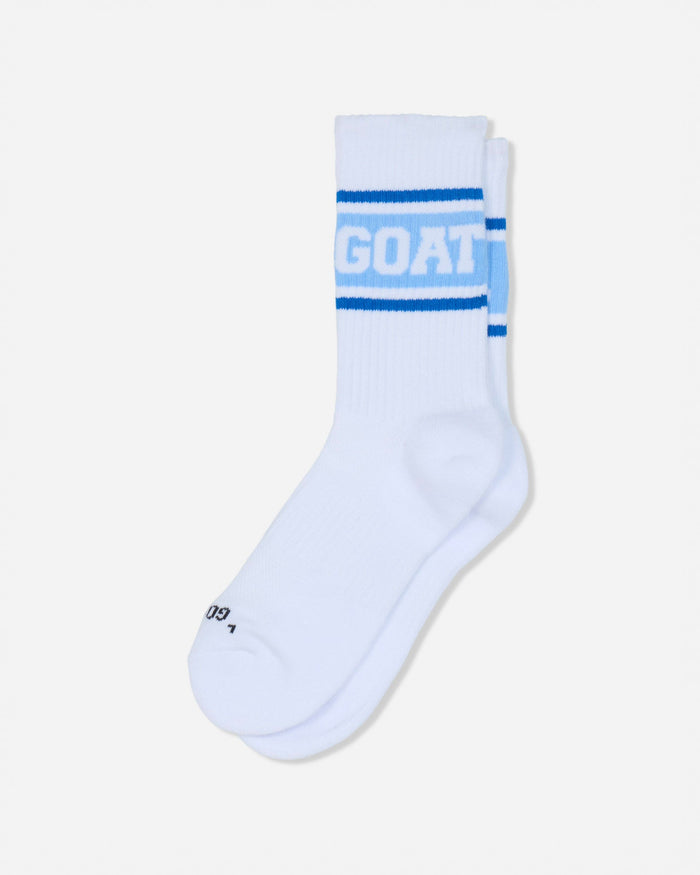 A pair of white crew socks with blue stripes and the word 'GOAT' printed in white on the front cuff, shown against a light gray background.#color_carolina-blue