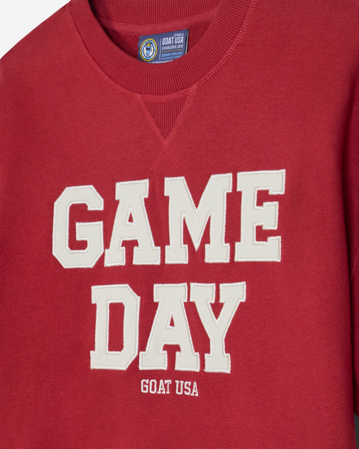 A close-up of a red french terry tee featuring the words 'GAME DAY' in large white varsity-style letters, with 'GOAT USA' printed underneath.#color_tomato