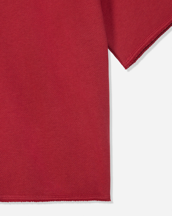 Close-up of a red short-sleeve garment showing the sleeve and hem against a light gray background.#color_tomato