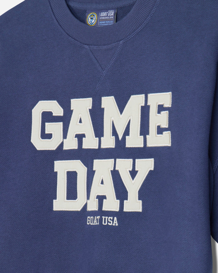 Close-up of a blue french terry tee featuring the words 'GAME DAY' in large white varsity-style letters, with 'GOAT USA' printed below in smaller white text.#color_navy