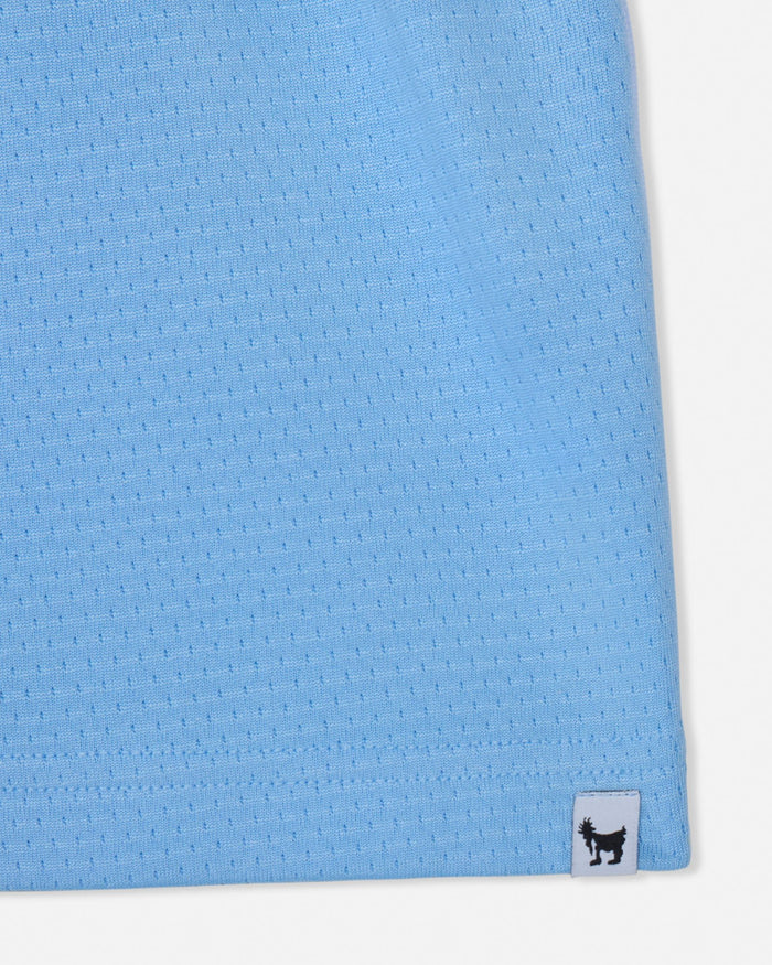 Close-up of a blue textured fabric with a brand label on a white background#color_carolina-blue