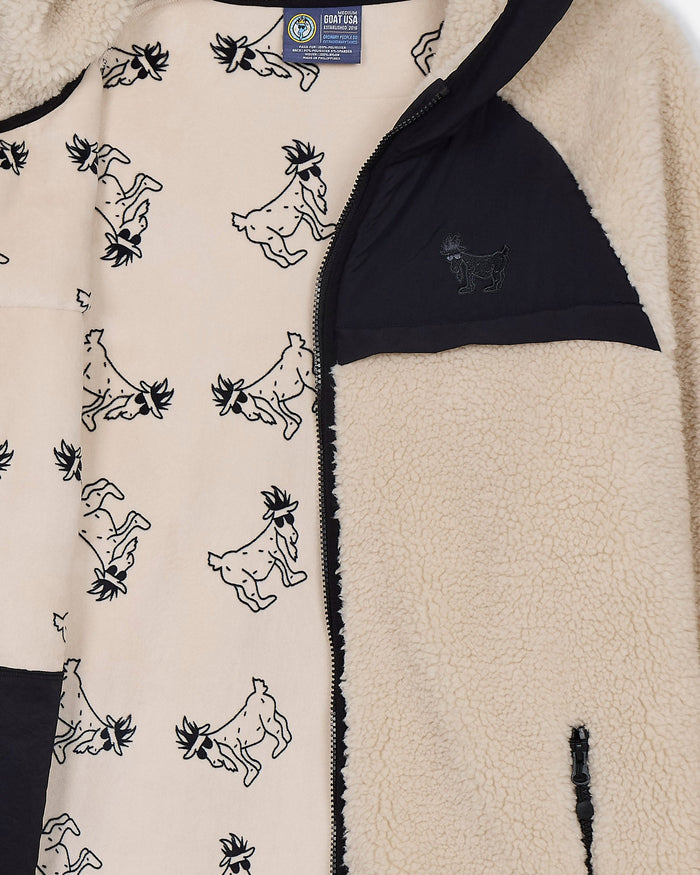 Close-up of a fleece jacket with goat pattern and visible brand label.#color_sandshell